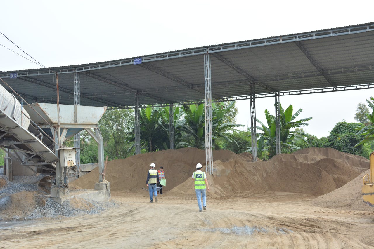 Crafting Captivating Headlines: Your awesome post title goes here Industrial construction site with workers inspecting sand piles under metal roofing.